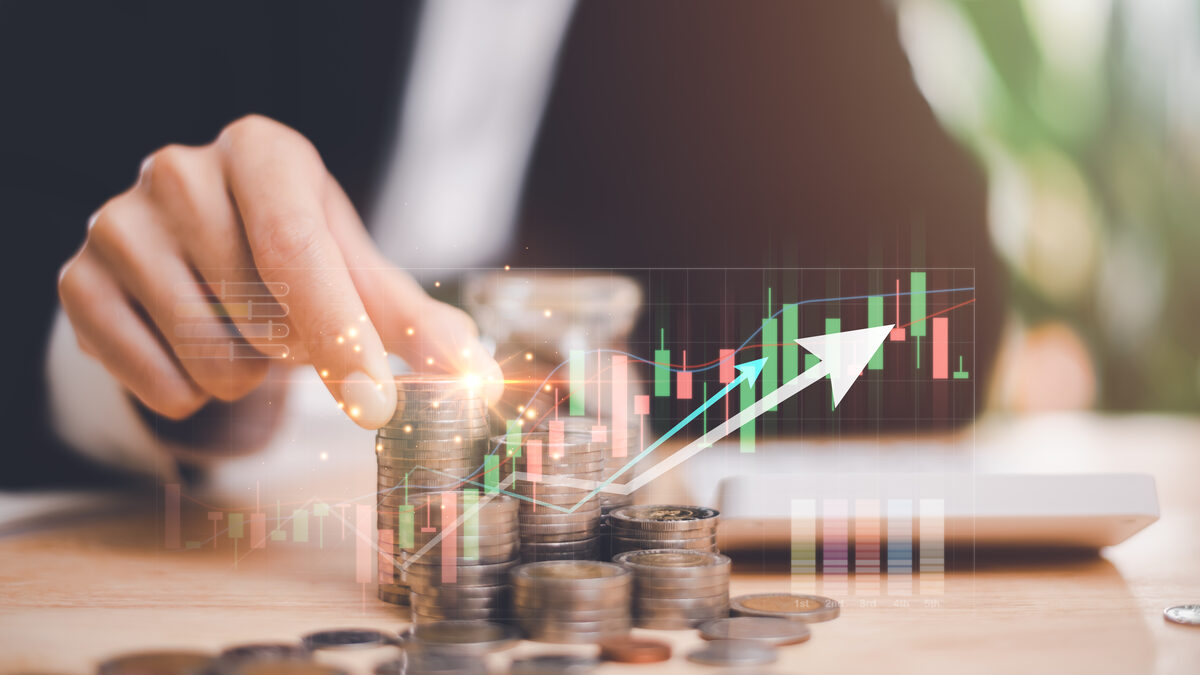 Businessperson stacking coins with a rising financial growth chart overlay